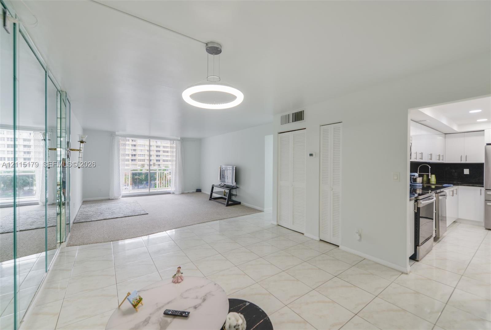 Large-format tile flooring, circular pendant lighting, wall-to-wall mirrored panels, and bi-fold closet doors