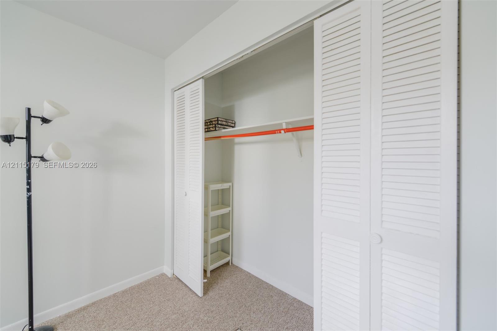 Closet featuring white louvered bifold doors, an integrated hanging rod, and a built-in overhead shelf