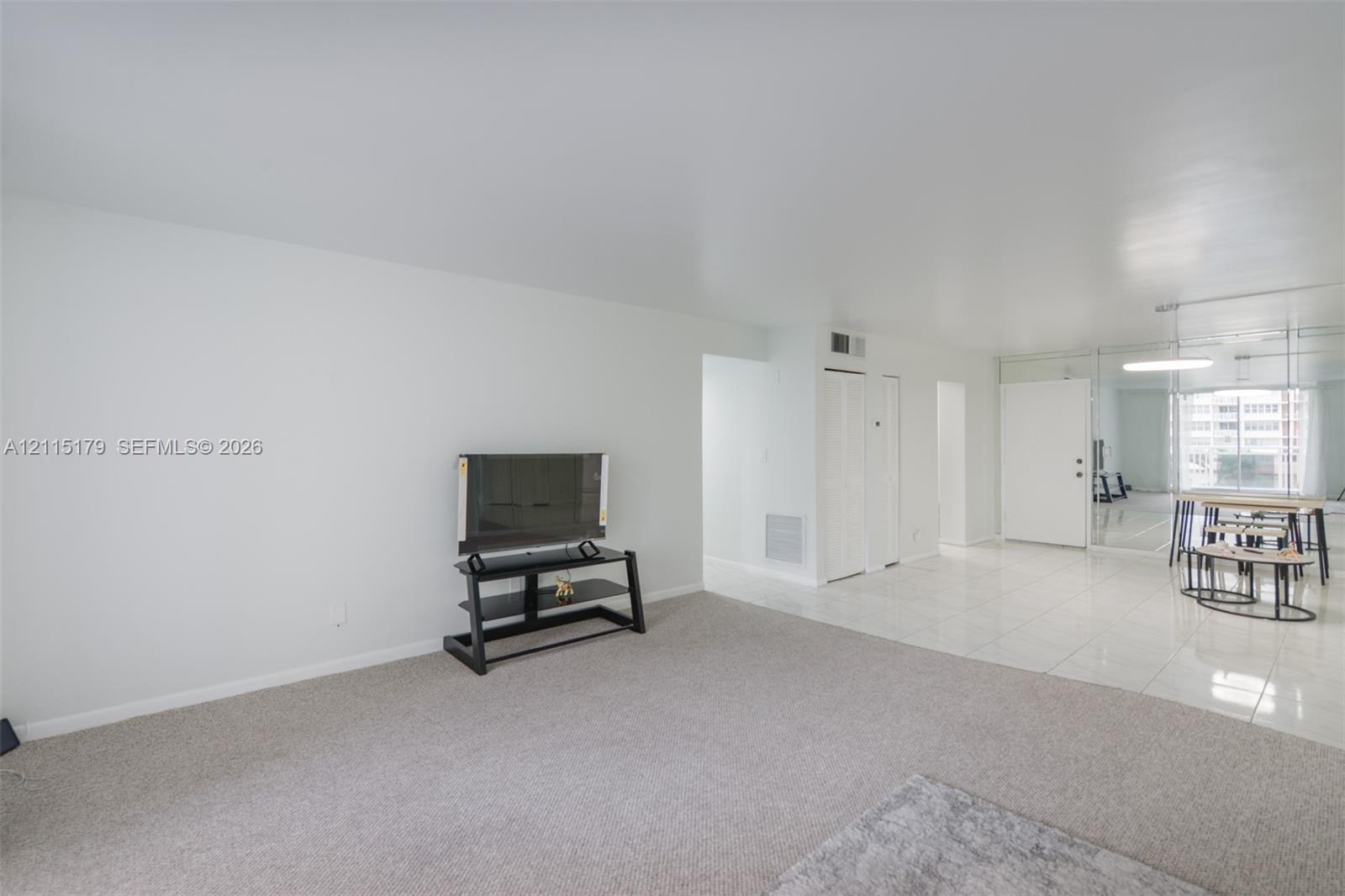 Interior space featuring light-toned carpeting, reflective tile flooring, and a mirrored wall panel