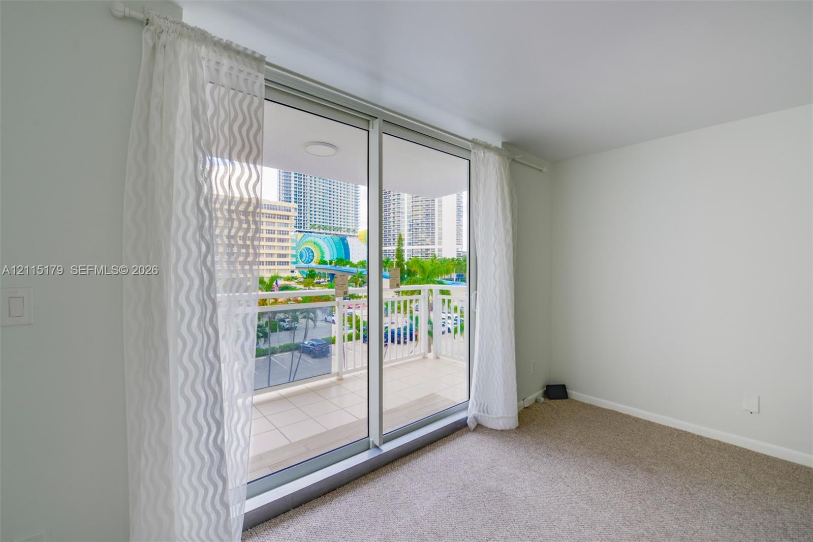 Floor-to-ceiling glass sliding doors opening to a private balcony featuring a metal railing