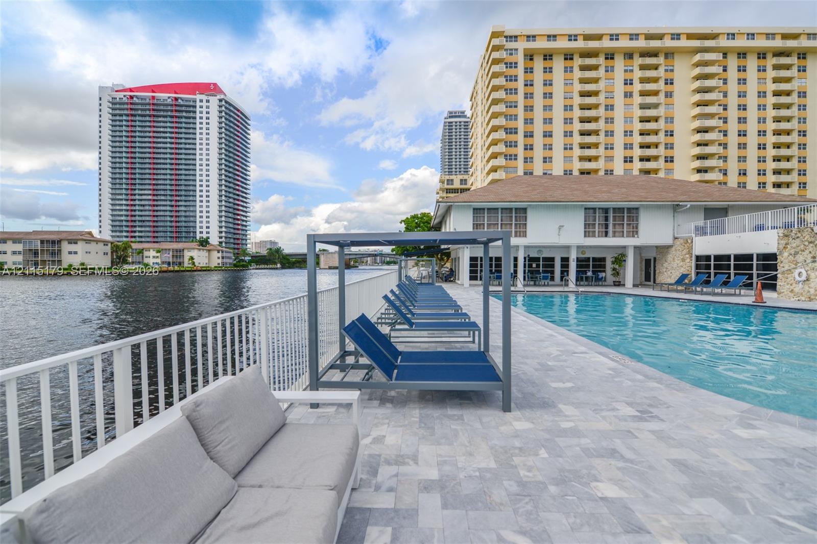 Waterfront swimming pool with light stone paver decking and white metal perimeter railing