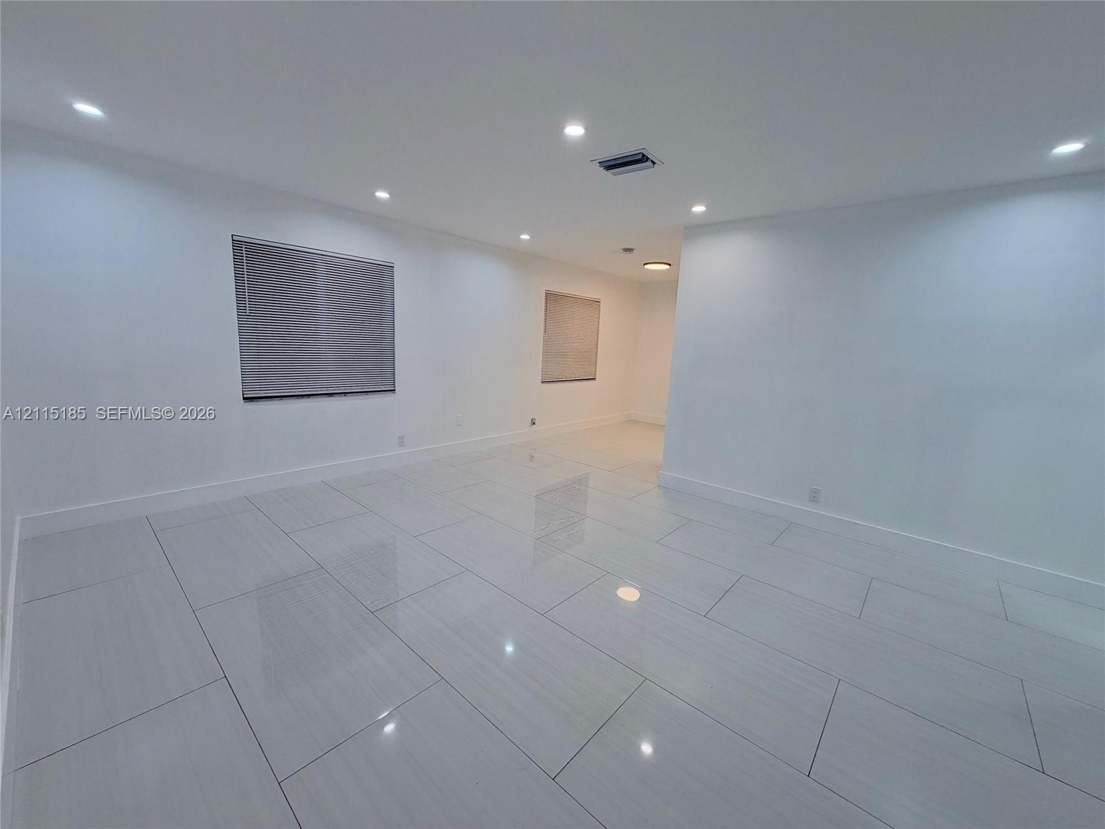 Large-format rectified tile flooring, recessed ceiling lighting, and neutral wall finishes
