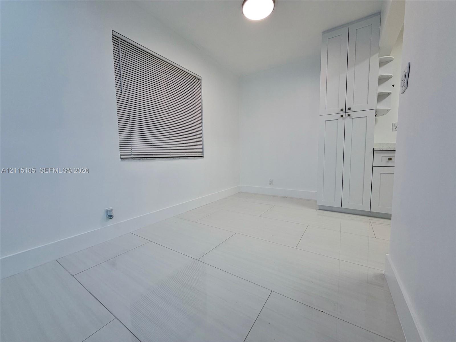Large-format tile flooring, built-in floor-to-ceiling cabinetry with shaker-style doors, and recessed ceiling lighting