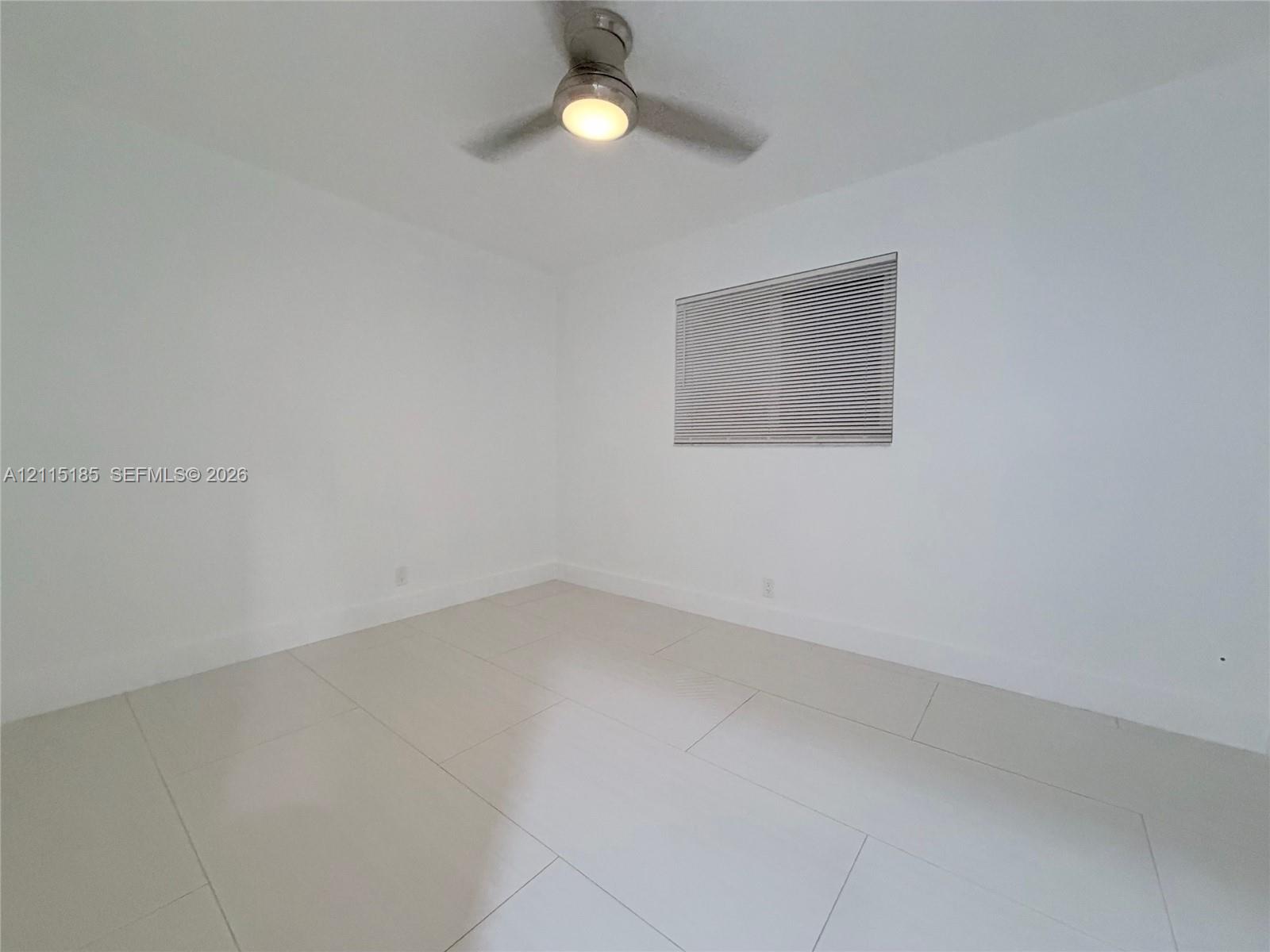 Neutral interior featuring white walls, large-format tile flooring, and a ceiling fan with integrated lighting