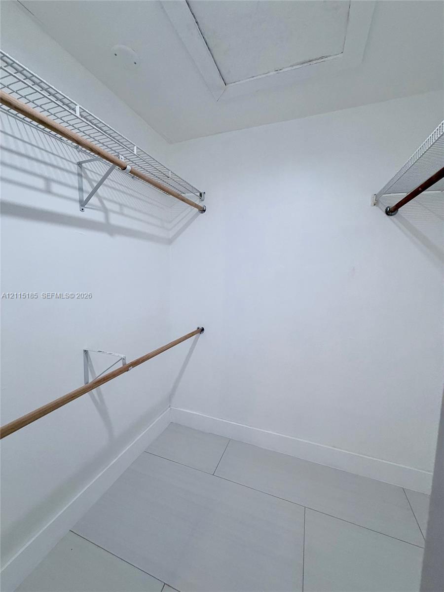 Walk-in closet featuring large-format tile flooring and tiered wire shelving with wood-finish rods