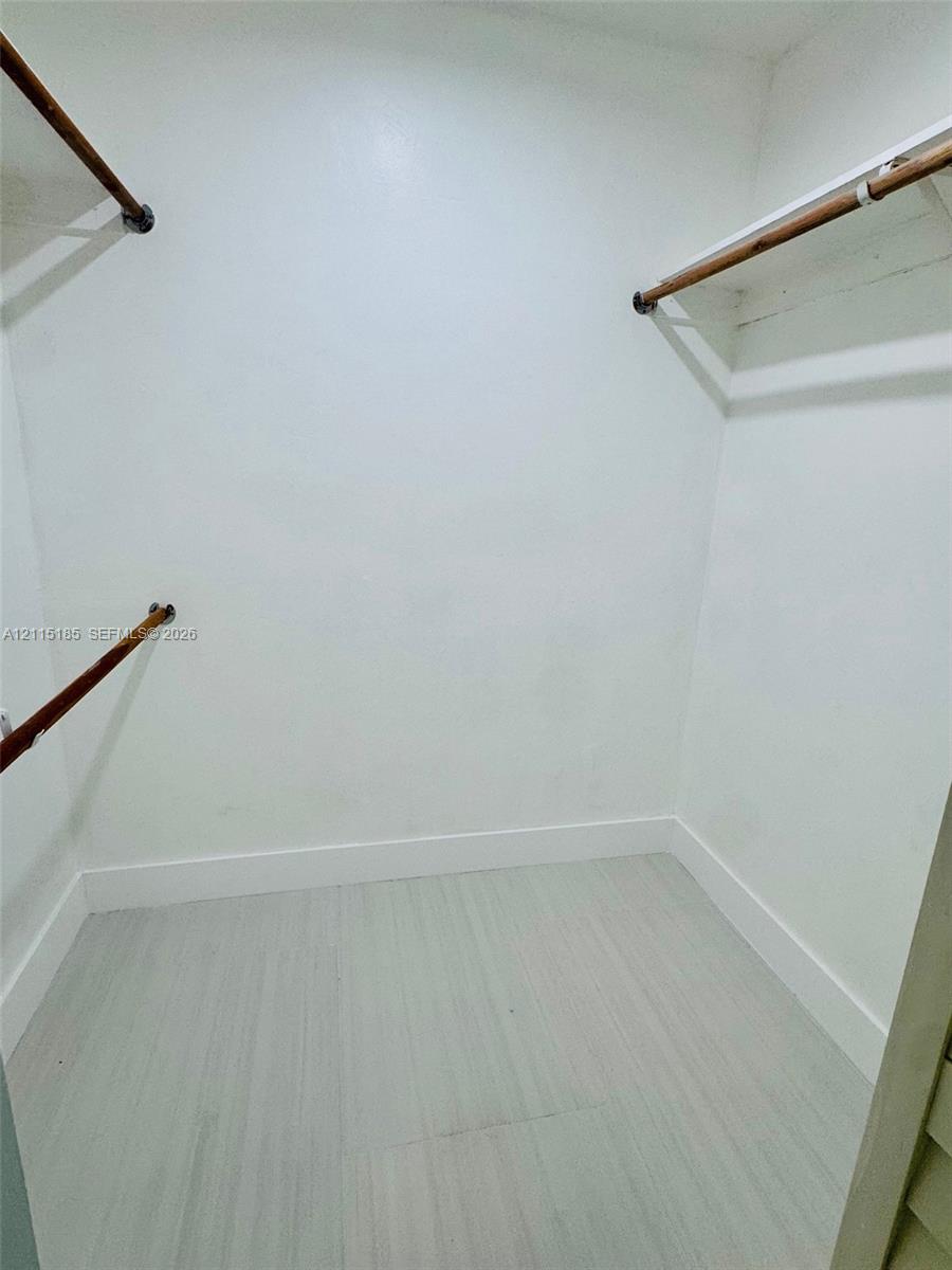 Storage space featuring installed wood-finish hanging rods and white shelving