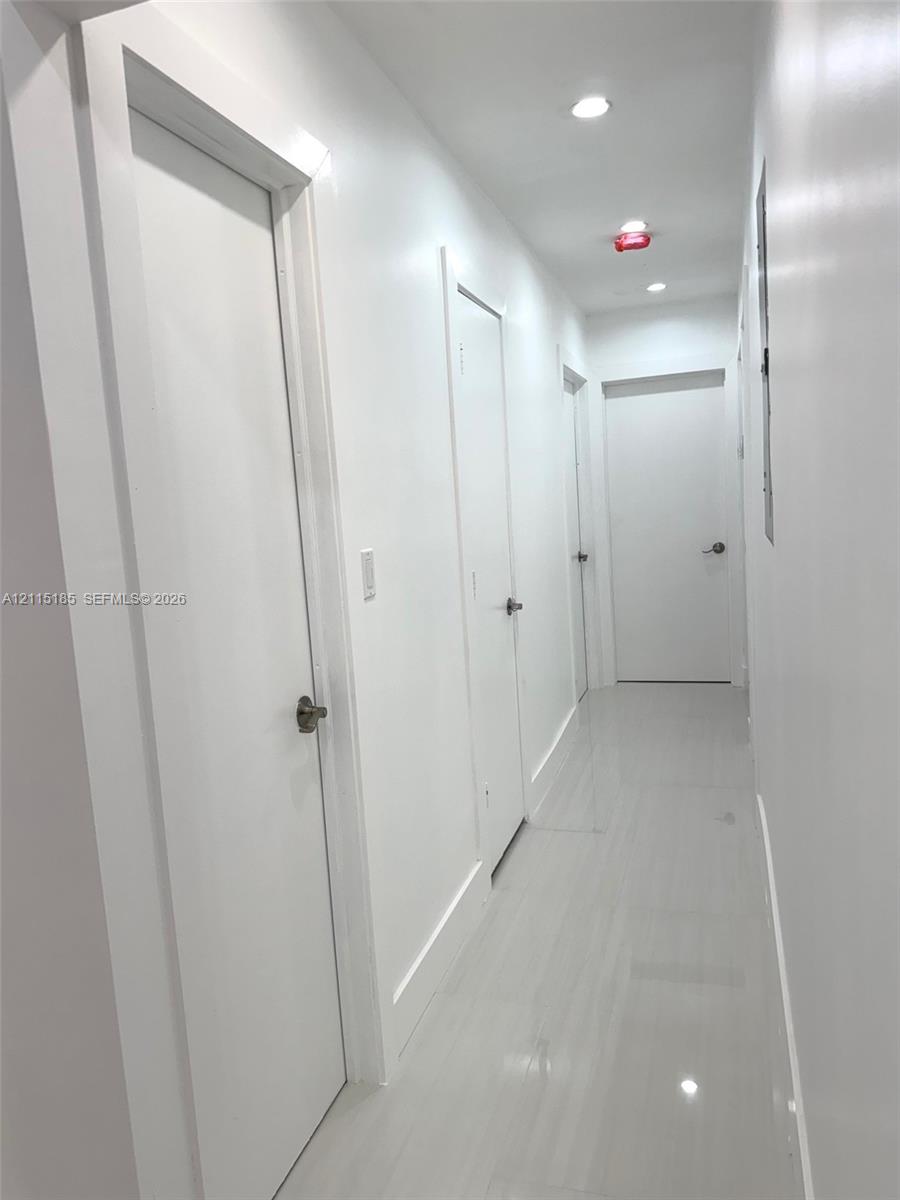 Hallway featuring polished tile flooring, smooth-finish walls, and recessed ceiling lighting