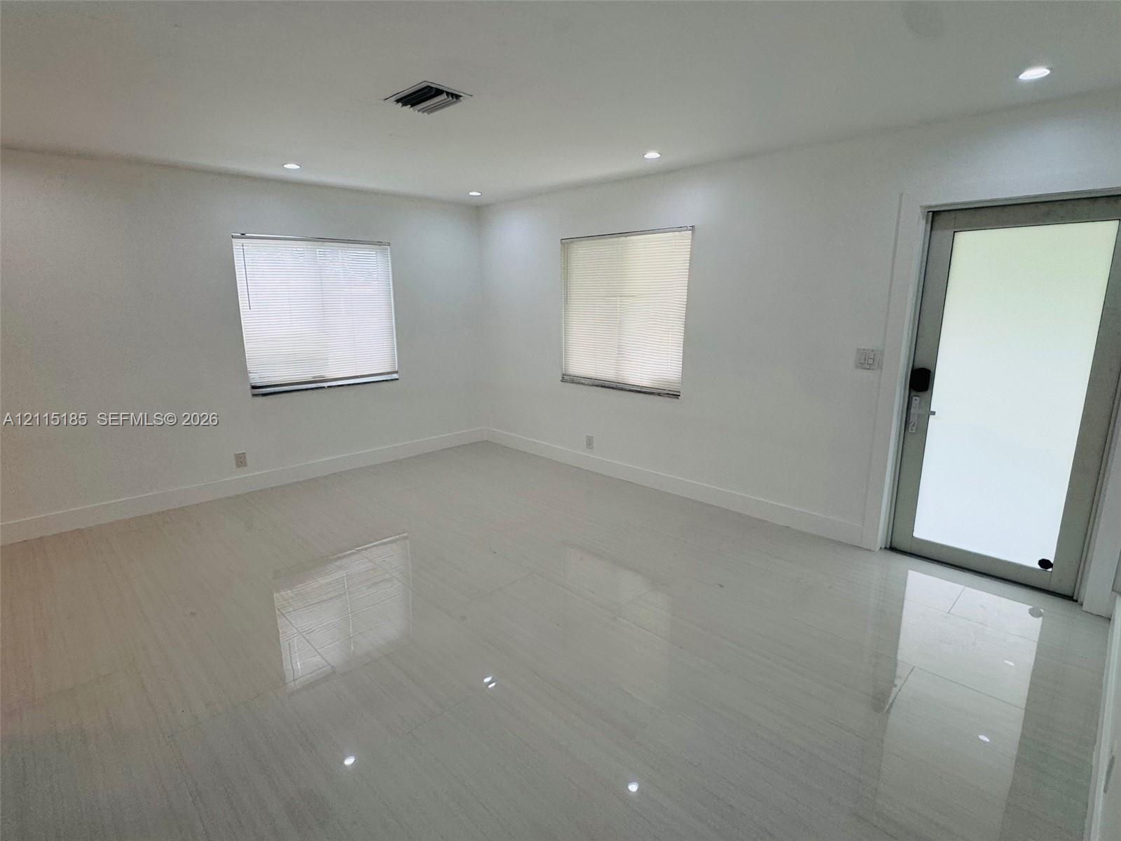 Neutral-toned space featuring polished tile flooring, recessed ceiling lighting, and a glass-paneled exterior door Neutral-toned space featuring polished tile flooring, recessed ceiling lighting, and a glass-paneled exterior door
