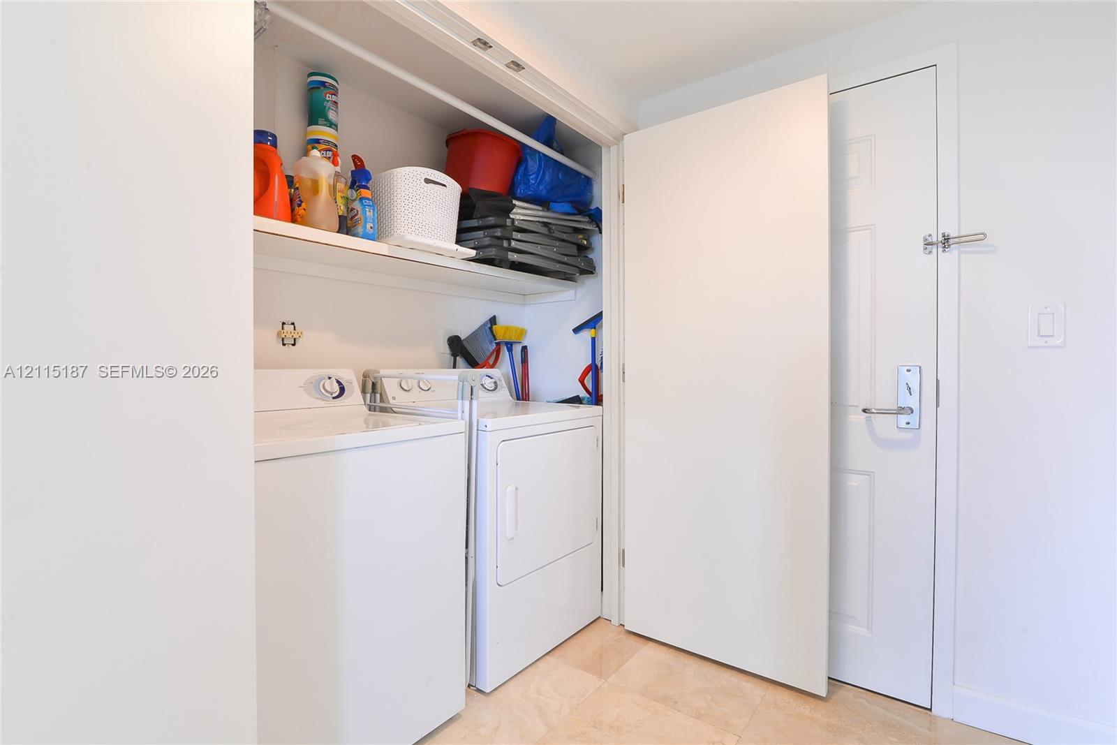 Laundry area featuring built-in overhead shelving, a side-by-side washer and dryer, and a neutral tile floor