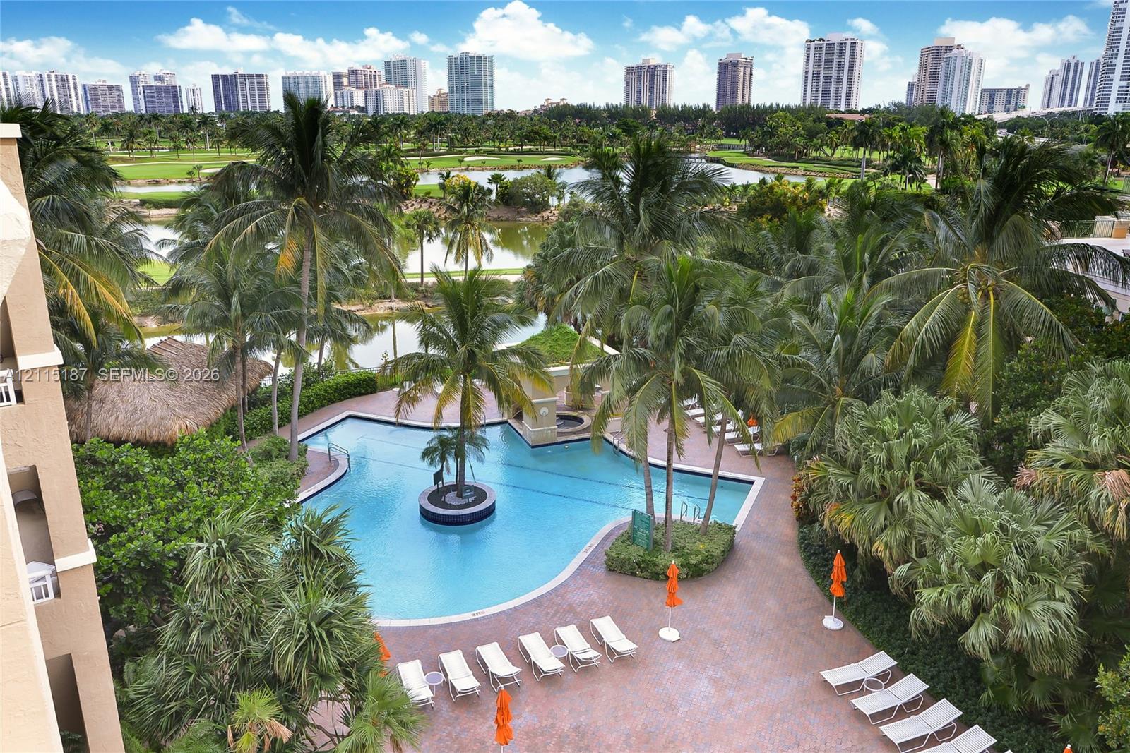 Swimming pool with a centered palm tree, paved pool deck, and mature palm landscaping