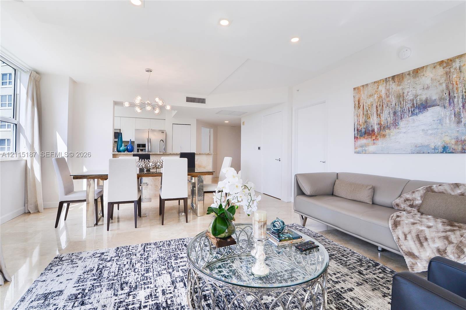 Open-concept interior featuring light stone flooring, recessed lighting, and a multi-globe chandelier Open-concept interior featuring light stone flooring, recessed lighting, and a multi-globe chandelier