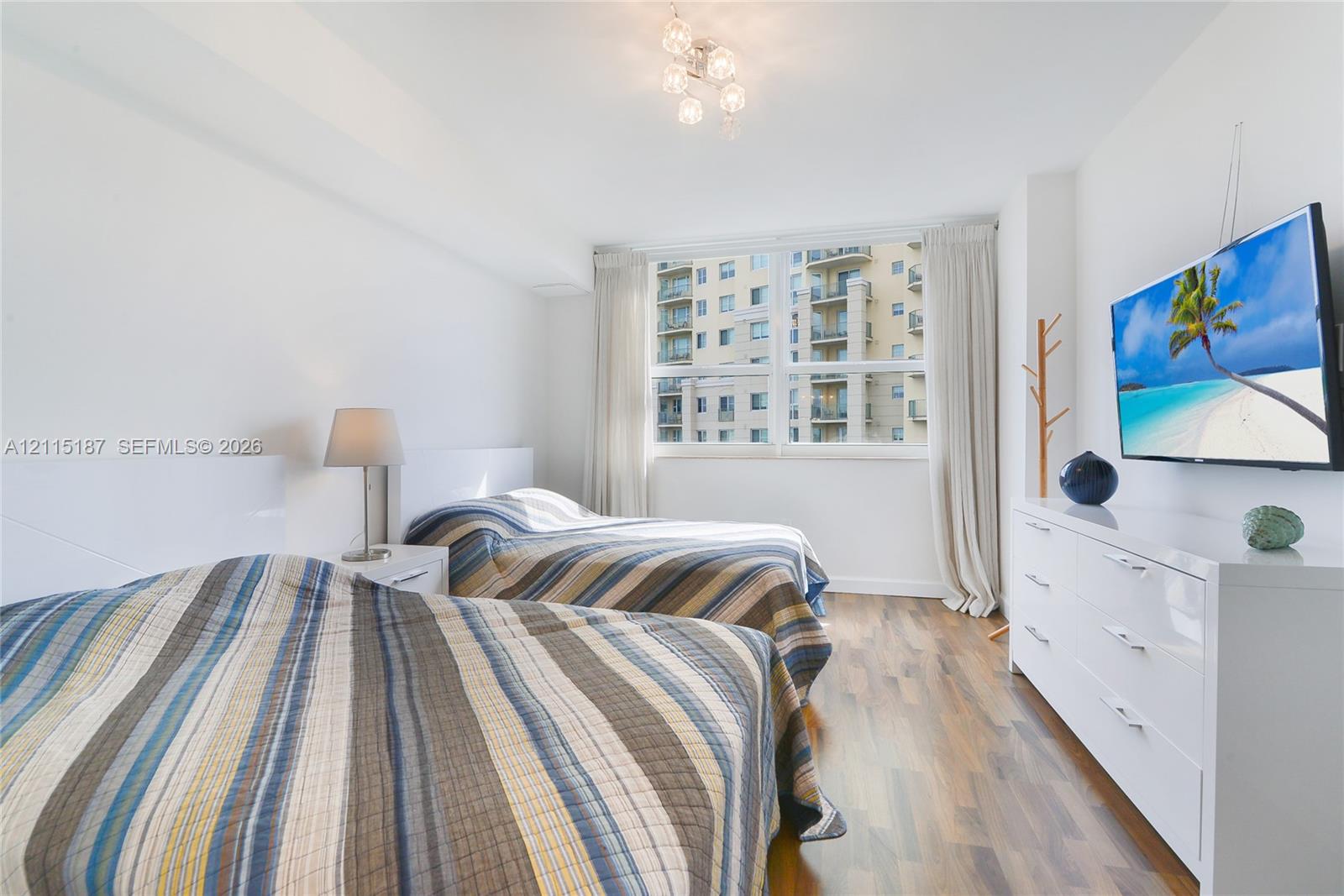 Room featuring large multi-pane windows, wood-finish flooring, and a contemporary multi-bulb ceiling fixture Room featuring large multi-pane windows, wood-finish flooring, and a contemporary multi-bulb ceiling fixture