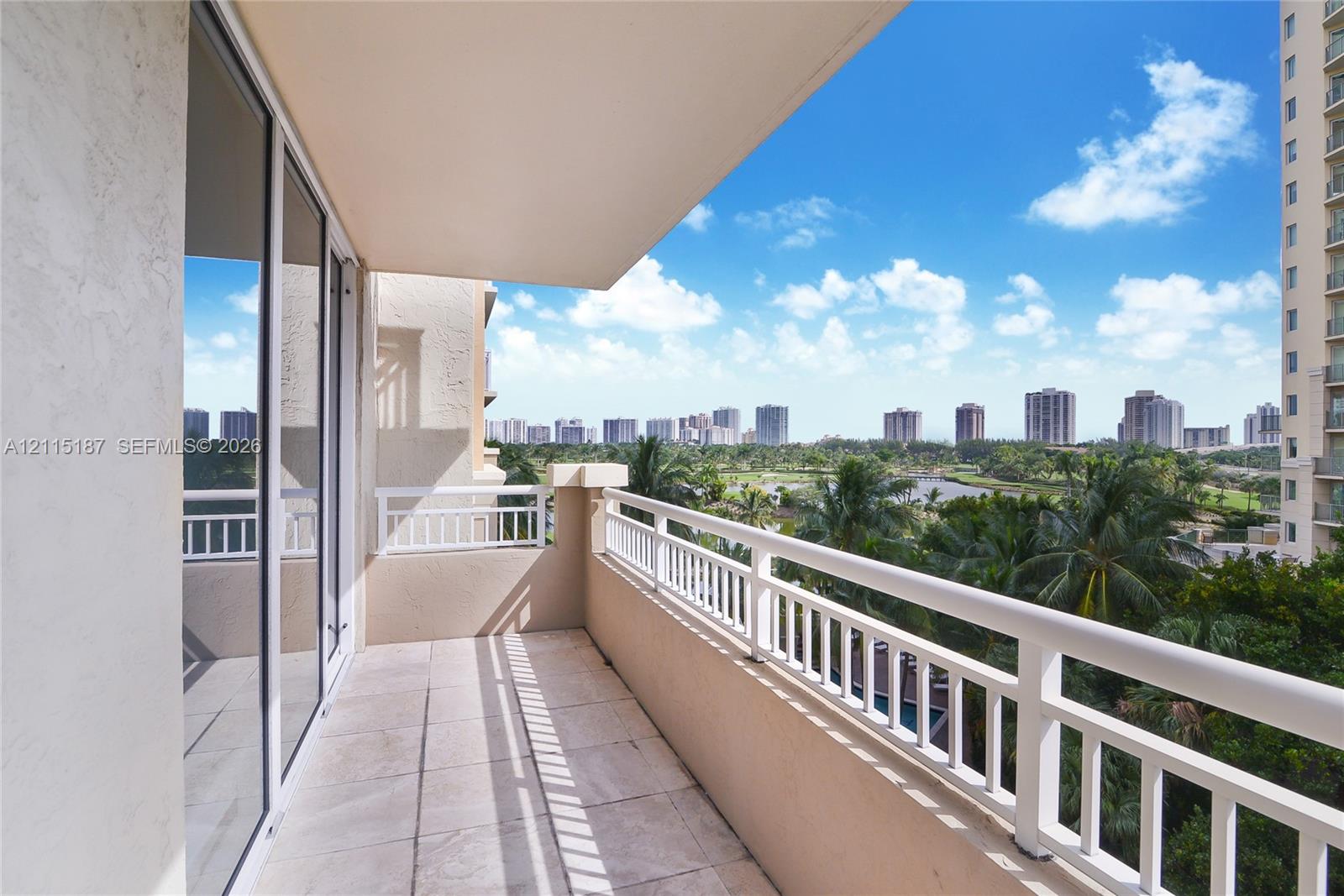 Covered balcony featuring tile flooring, metal railings, and floor-to-ceiling glass sliding doors