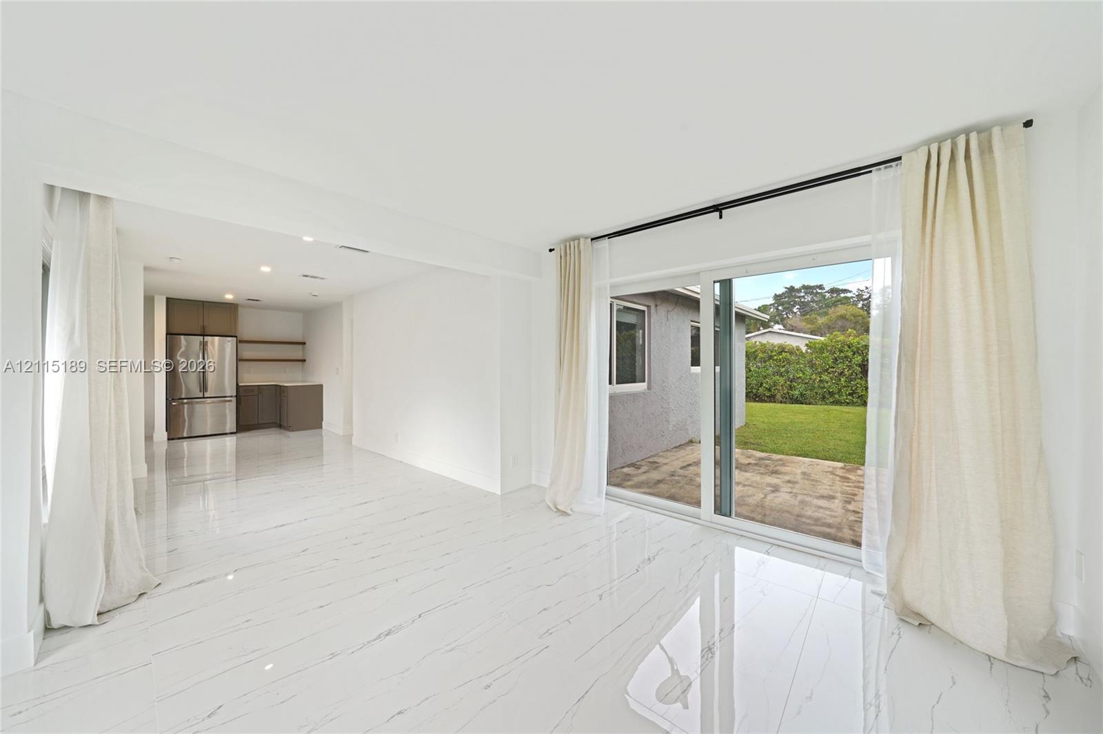 Open-concept interior featuring light-toned flooring, recessed lighting, sliding glass doors, and stainless steel kitchen appliances Open-concept interior featuring light-toned flooring, recessed lighting, sliding glass doors, and stainless steel kitchen appliances