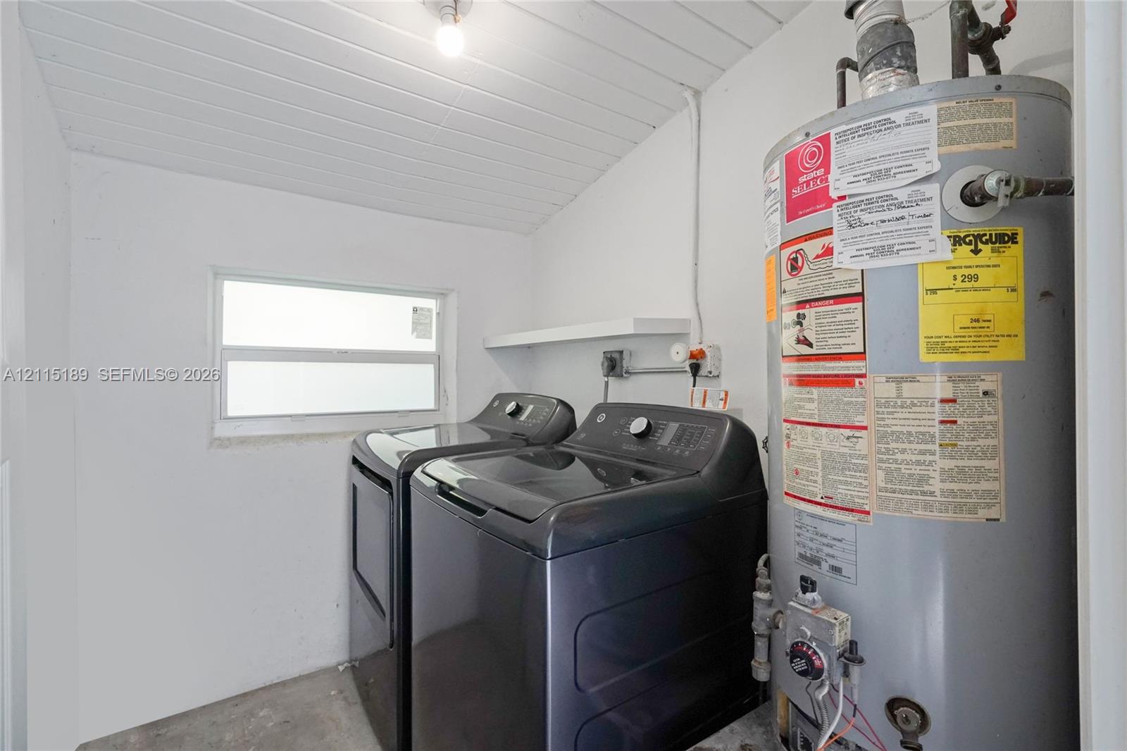Utility space featuring a horizontal sliding window, beadboard ceiling, white wall finish, and a built-in wall shelf