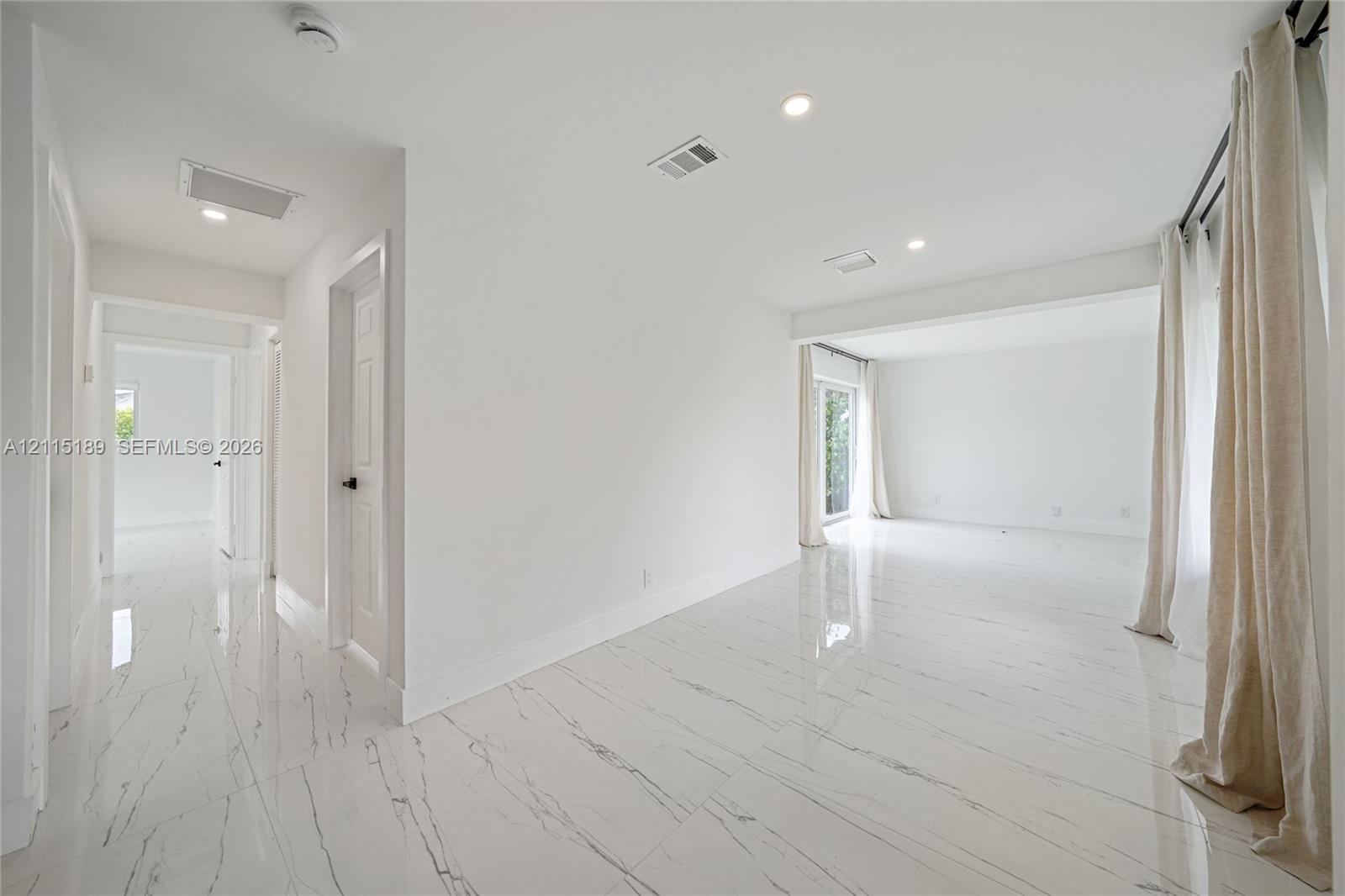 Polished stone-finish flooring with veining, recessed lighting, and crisp white wall finishes Polished stone-finish flooring with veining, recessed lighting, and crisp white wall finishes
