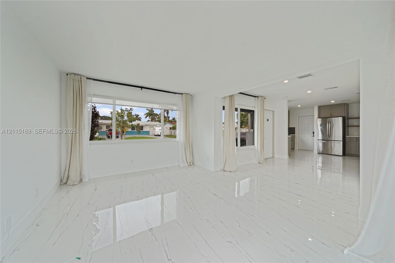 Open-concept interior featuring polished tile flooring, large multi-pane windows, recessed ceiling lighting, and stainless steel kitchen appliances Open-concept interior featuring polished tile flooring, large multi-pane windows, recessed ceiling lighting, and stainless steel kitchen appliances