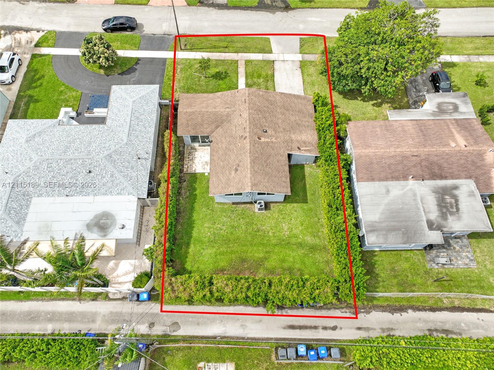Aerial perspective of property featuring an expansive backyard, mature hedge perimeter, concrete patio, and dedicated driveway