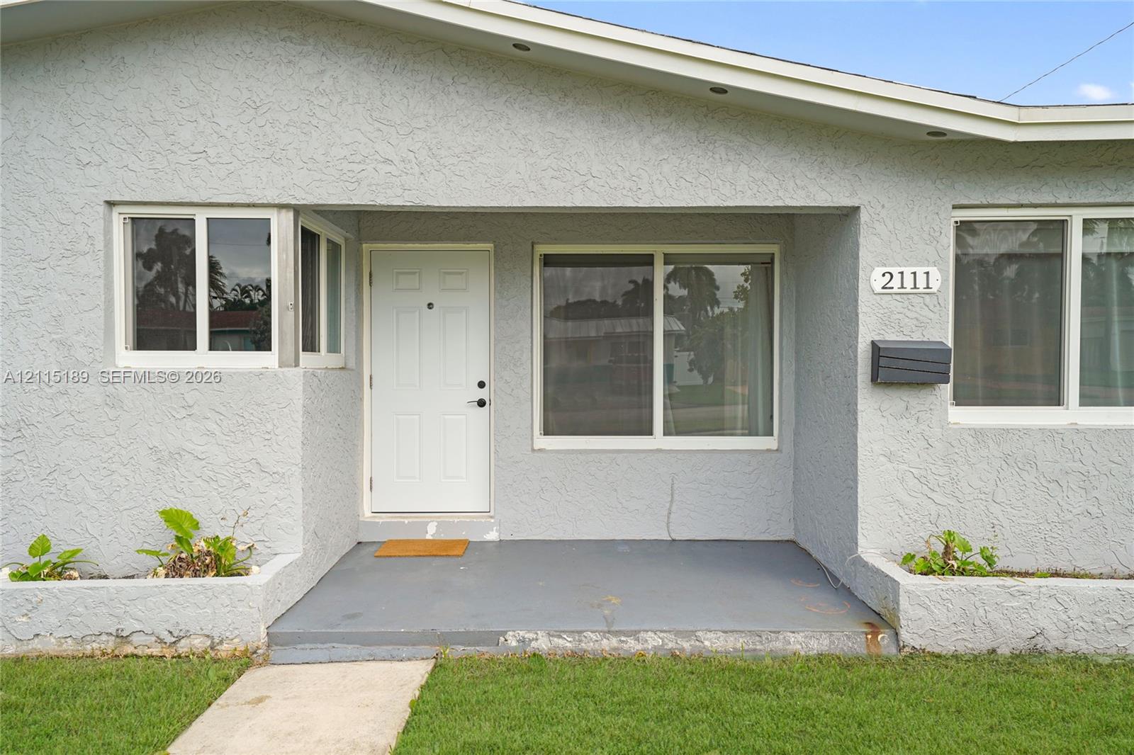 Stucco exterior featuring a covered entryway, integrated concrete planters, sliding windows, and a multi-pane front door Stucco exterior featuring a covered entryway, integrated concrete planters, sliding windows, and a multi-pane front door