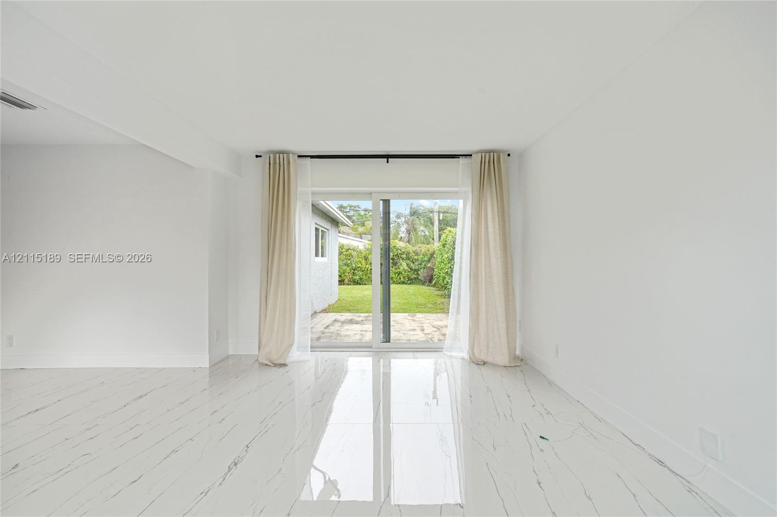 Interior space featuring large-format tile flooring with veining, white walls, and a sliding glass door