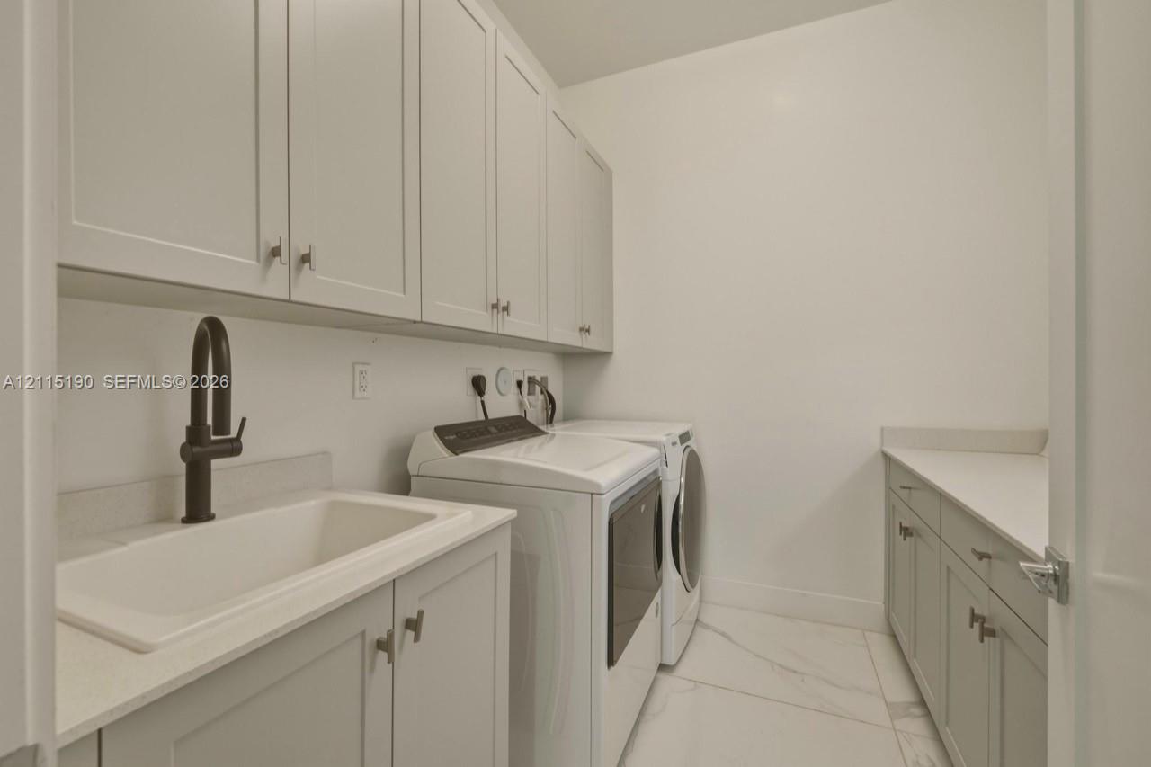 Laundry room with sink and cabinetry.