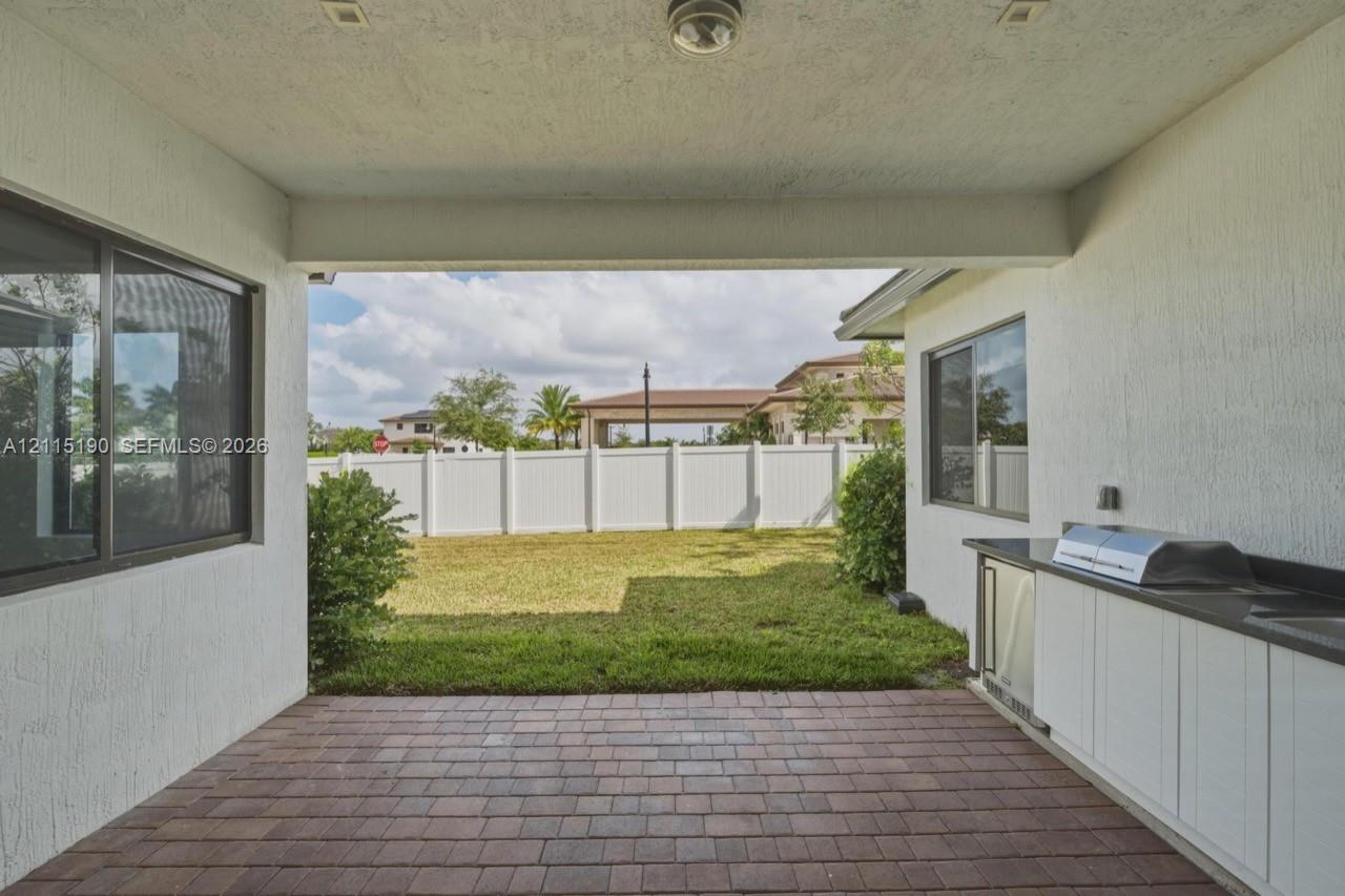 Covered patio with outdoor kitchen and built-in grill.