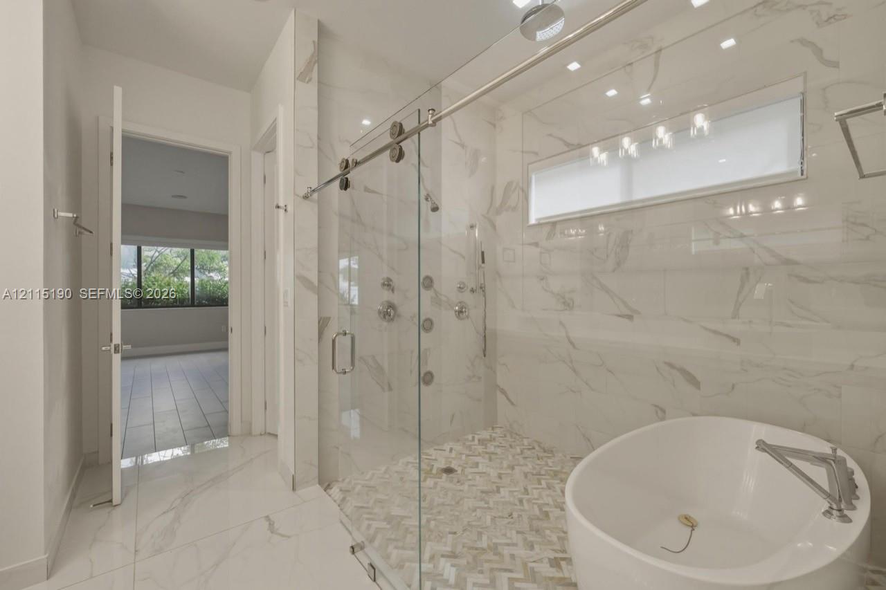 Bathroom with freestanding tub and separate glass-enclosed shower.
