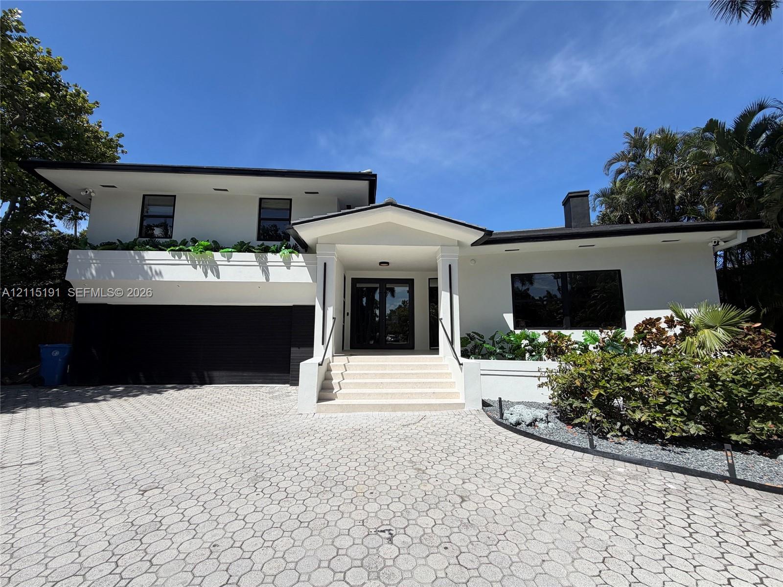 Two-story exterior featuring white stucco finish, geometric paver driveway, recessed lighting, integrated garage, and a covered entryway with concrete steps Two-story exterior featuring white stucco finish, geometric paver driveway, recessed lighting, integrated garage, and a covered entryway with concrete steps