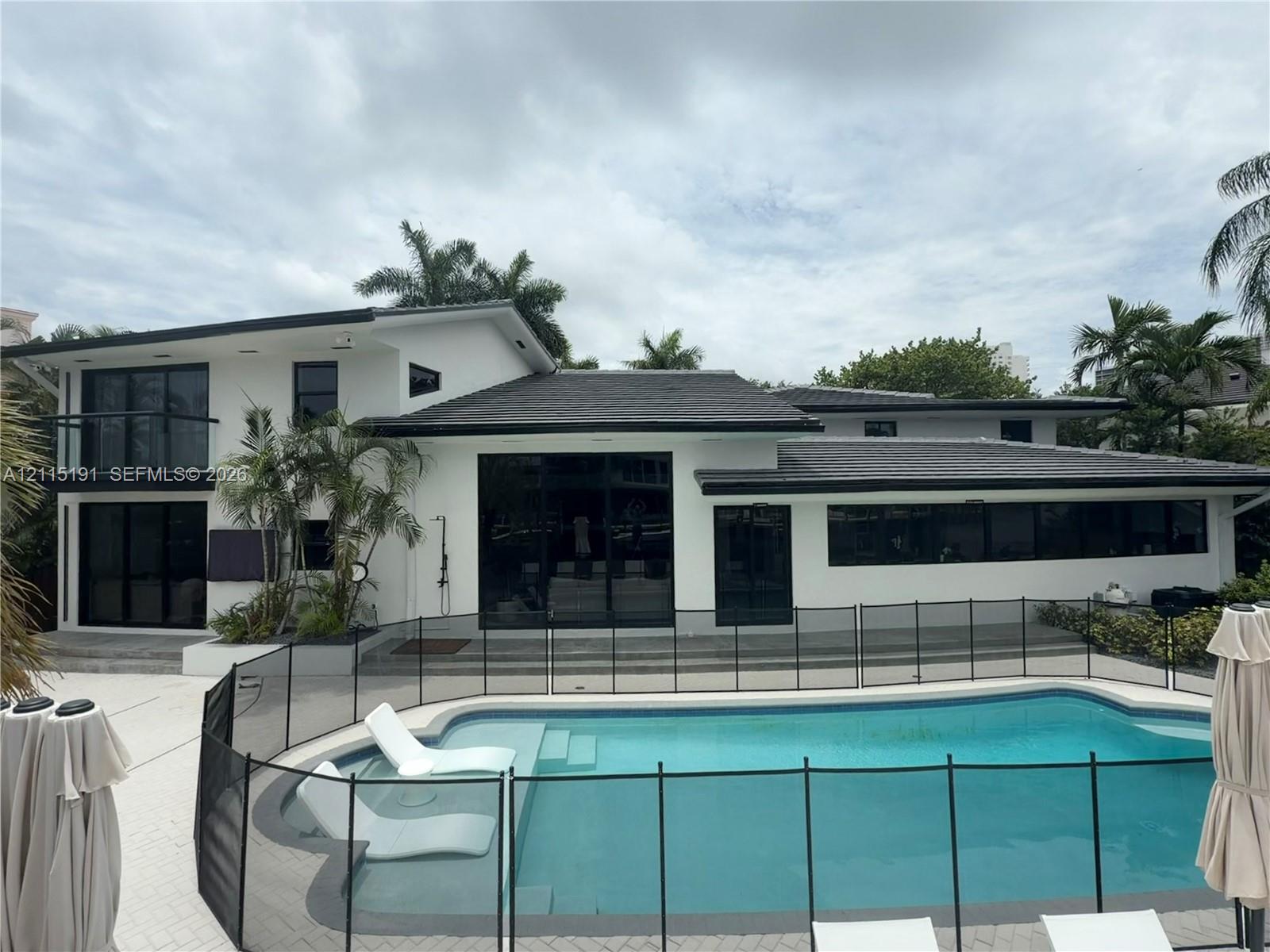Modern exterior featuring a two-story design with a flat roof, large glass sliding doors, a second-level balcony, and a swimming pool with integrated sun shelf Modern exterior featuring a two-story design with a flat roof, large glass sliding doors, a second-level balcony, and a swimming pool with integrated sun shelf