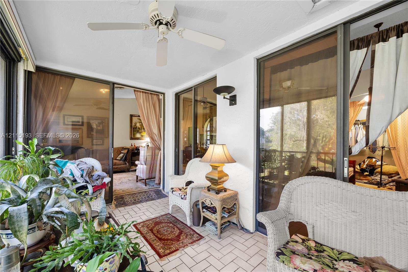 Enclosed patio featuring ceramic tile flooring, a ceiling-mounted fan, and wall-mounted light fixtures with large glass sliding doors