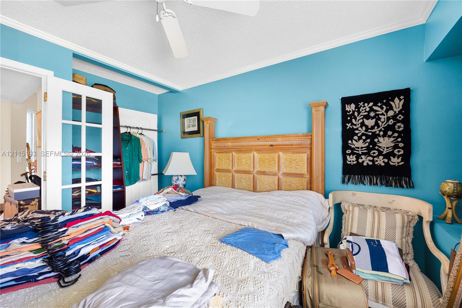 French-door closet entry featuring white trim, ceiling-mounted paddle fan, and crown molding