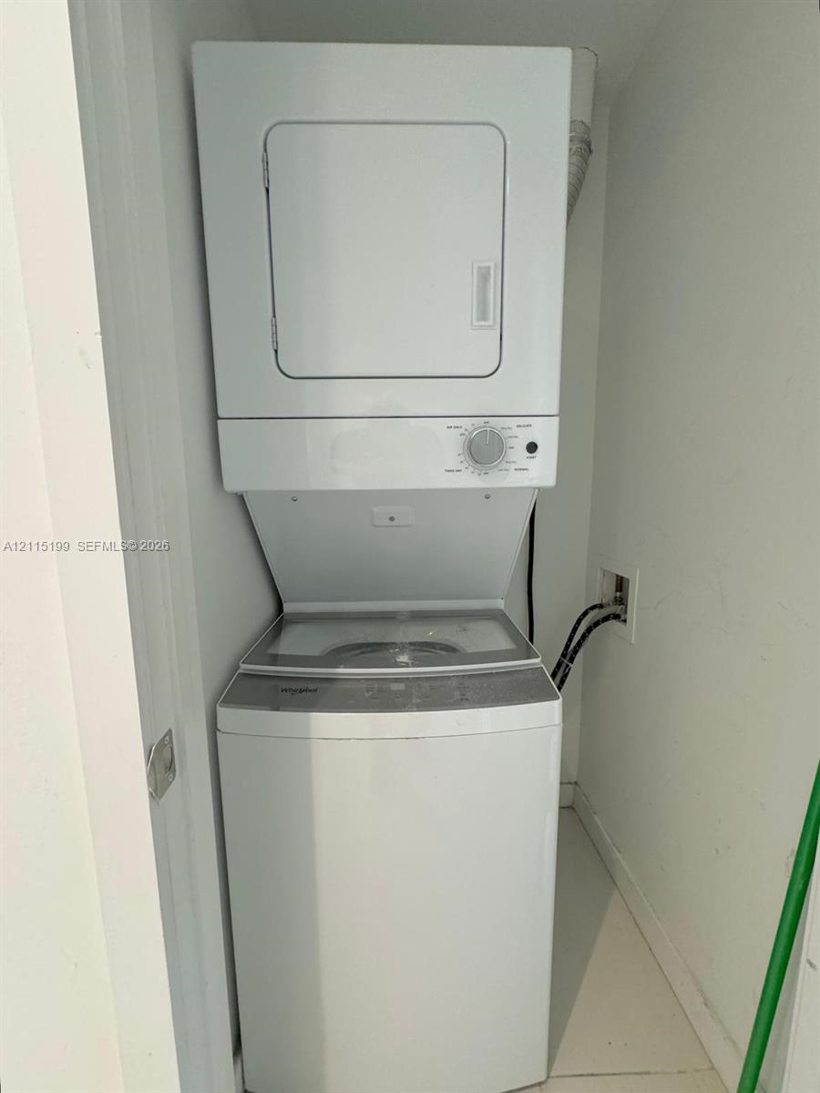 Stacked white laundry center featuring a top-loading washer and front-loading dryer unit housed within a dedicated enclosure