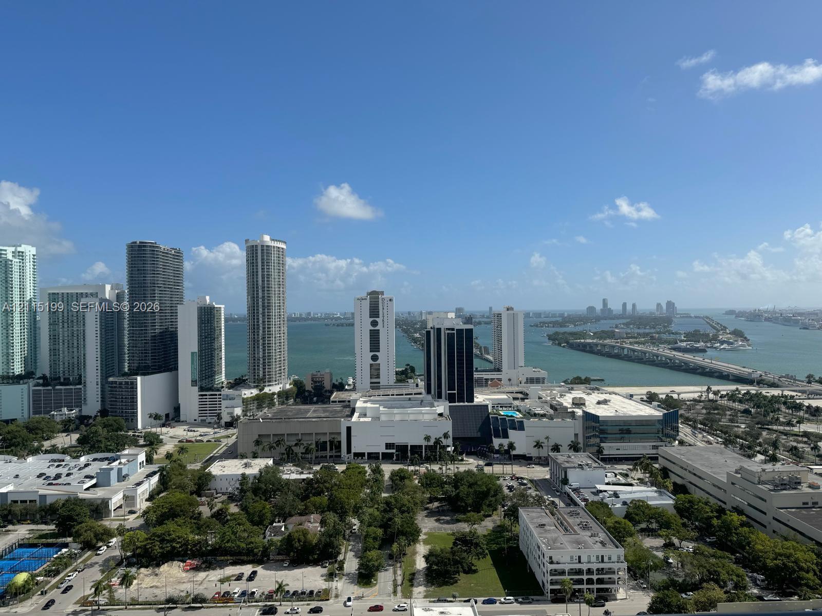 Elevated perspective of the metropolitan skyline featuring expansive waterfront stretches, high-rise buildings, and bridge infrastructure