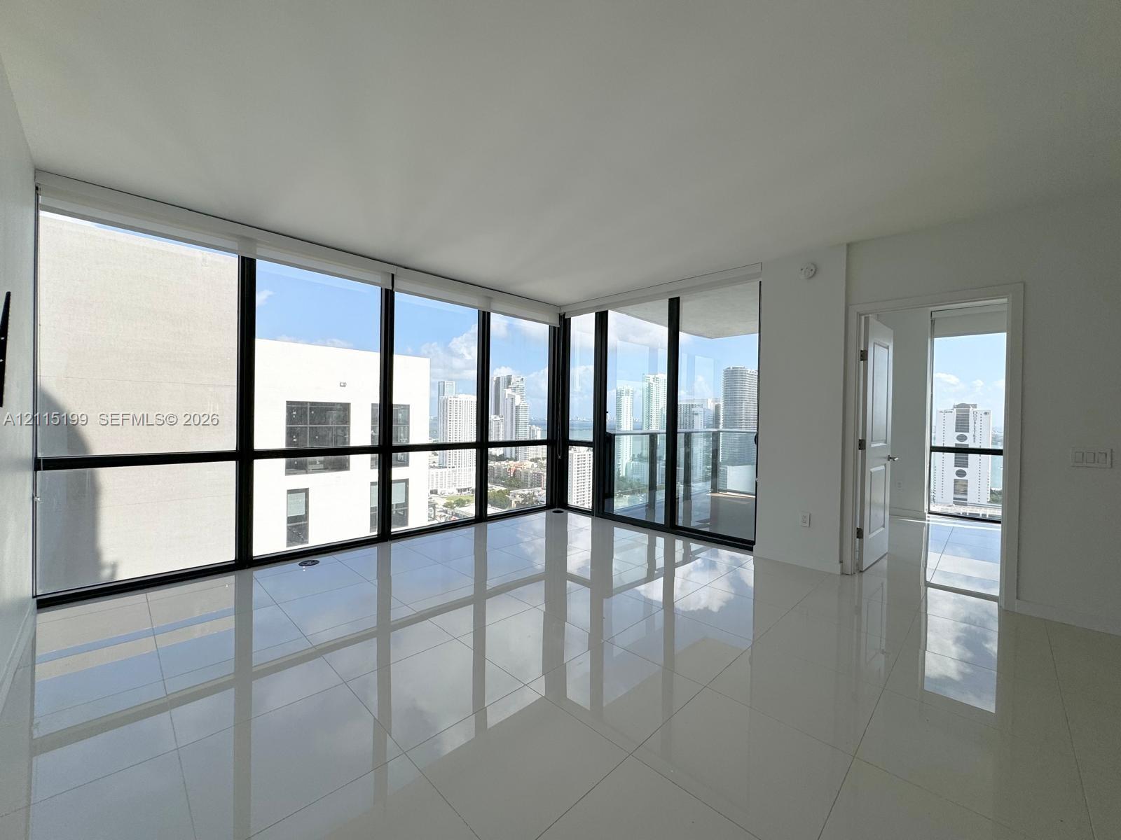 Floor-to-ceiling windows, high-gloss tile flooring, and a glass-paneled balcony door