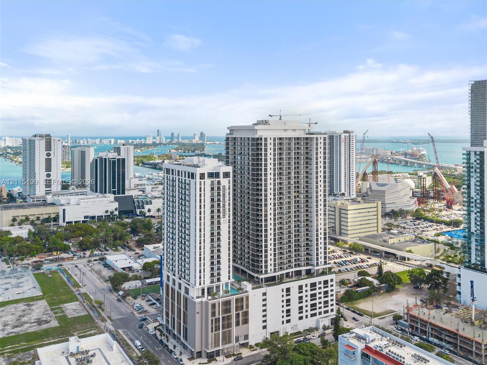 High-rise residential tower featuring a concrete and glass facade, private balconies, an elevated outdoor pool deck, and a multi-level parking structure