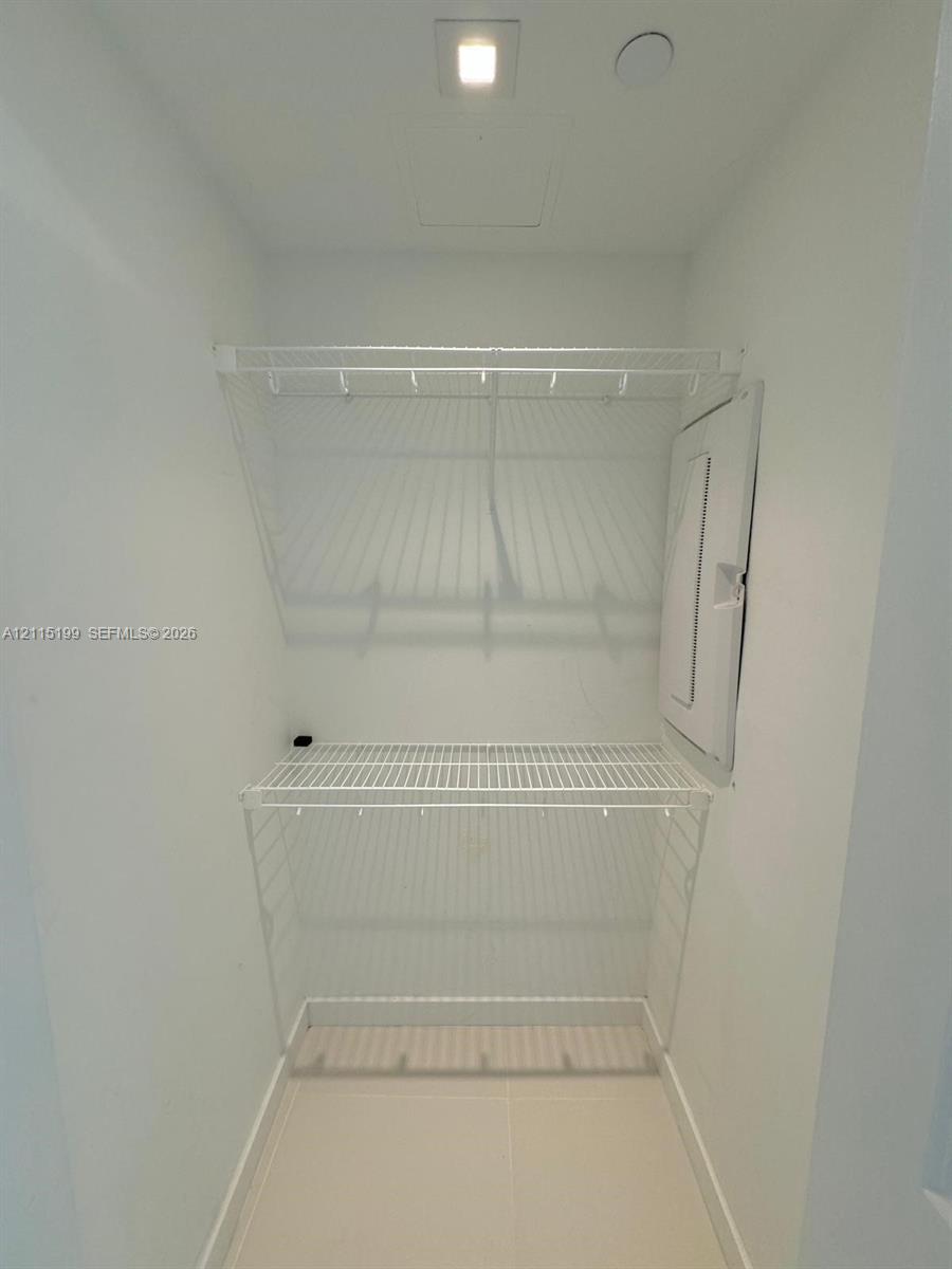Storage space featuring tiered white wire shelving and overhead recessed lighting