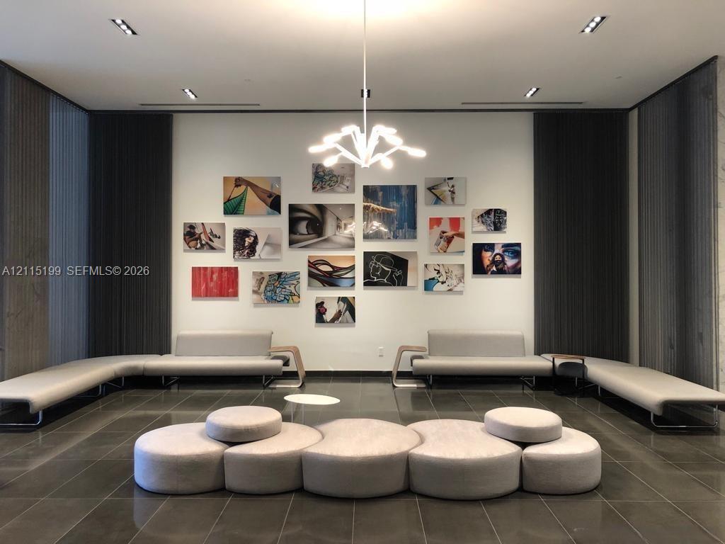 High-ceilinged interior featuring large-format tile flooring, recessed architectural lighting, and a multi-arm modern pendant fixture