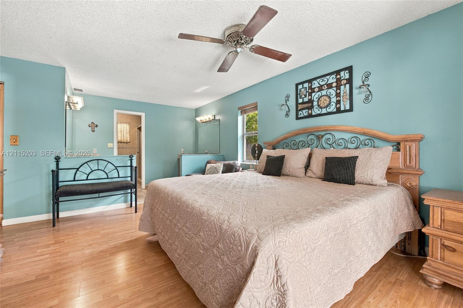 Wood-finish flooring, ceiling fan with light fixture, wall-mounted vanity lighting, and natural light via single-pane window