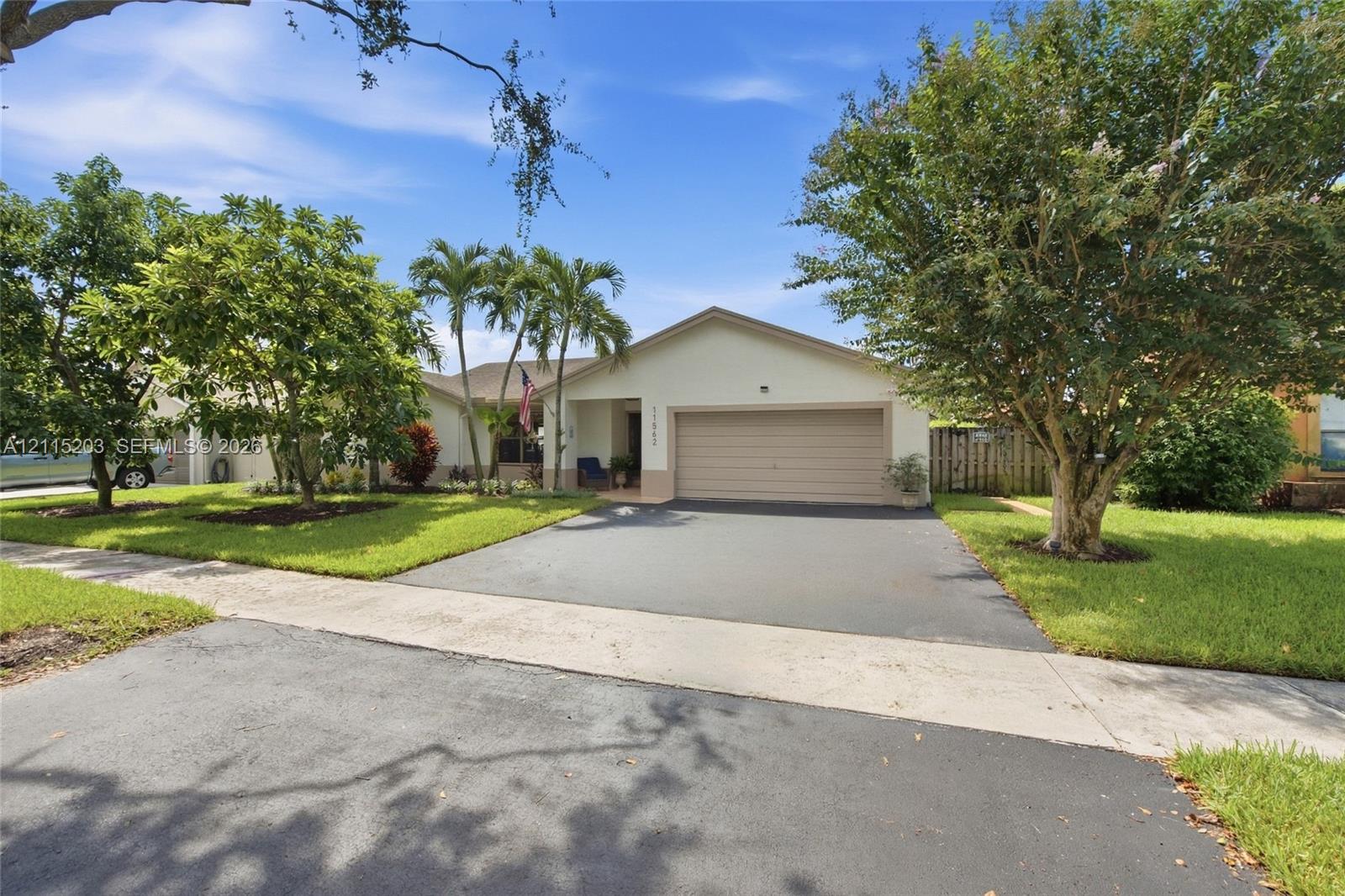 Single-story exterior featuring a stucco facade, an attached two-car garage, an extra wide asphalt driveway, and mature landscaping Single-story exterior featuring a stucco facade, an attached two-car garage, an extra wide asphalt driveway, and mature landscaping