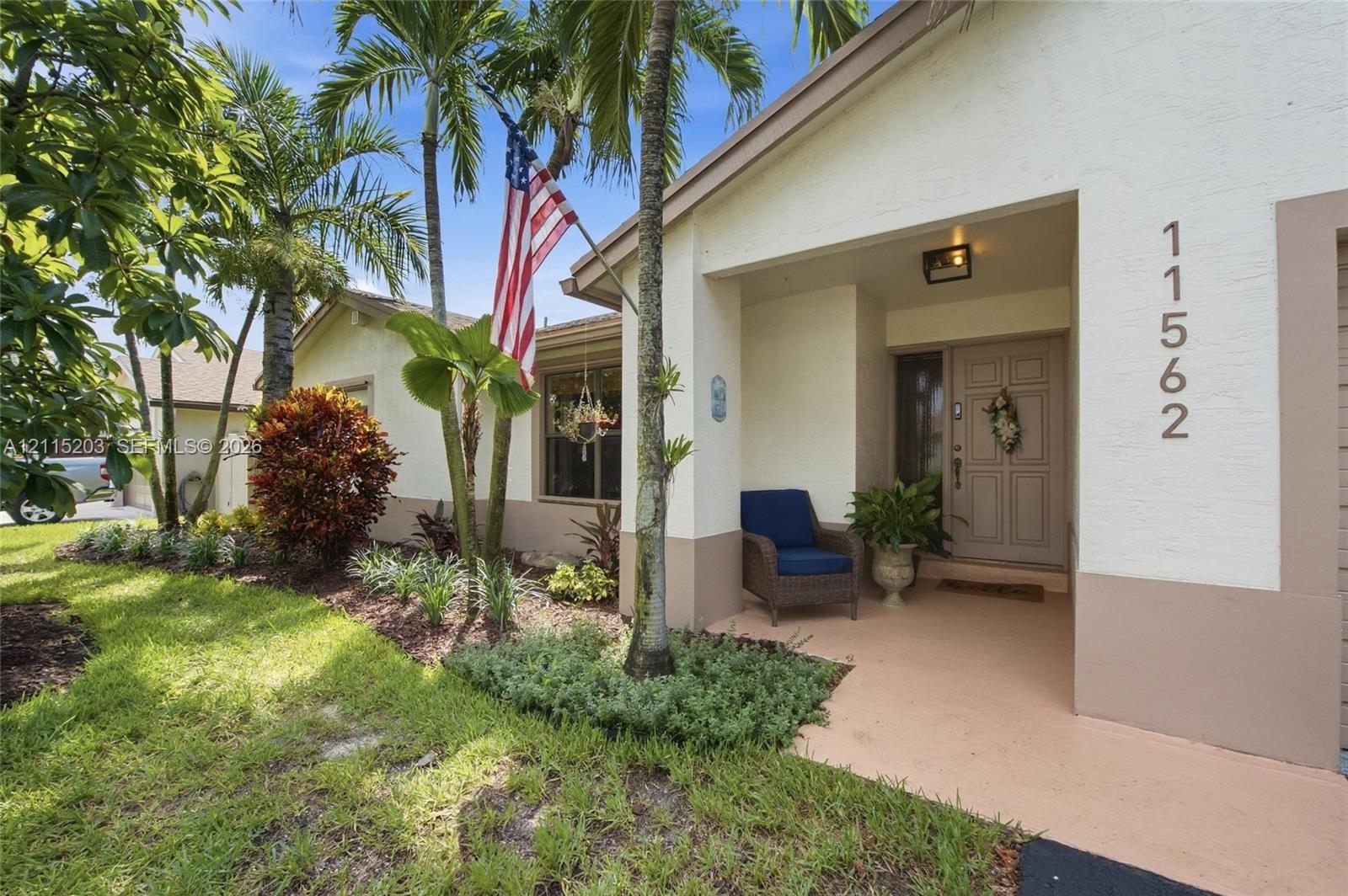 Recessed covered entryway, multi-paneled front door, and mature tropical landscaping with lighting Recessed covered entryway, multi-paneled front door, and mature tropical landscaping with lighting