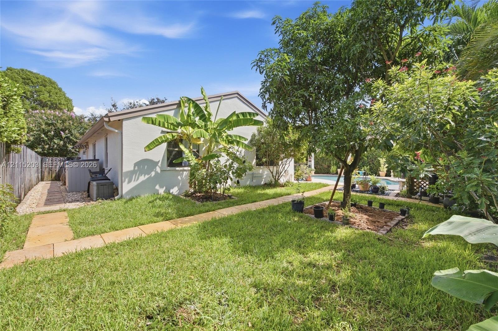 Backyard featuring a paved stone walkway, established landscaping, mature fruit trees, wood fence, and a swimming pool Backyard featuring a paved stone walkway, established landscaping, mature fruit trees, wood fence, and a swimming pool