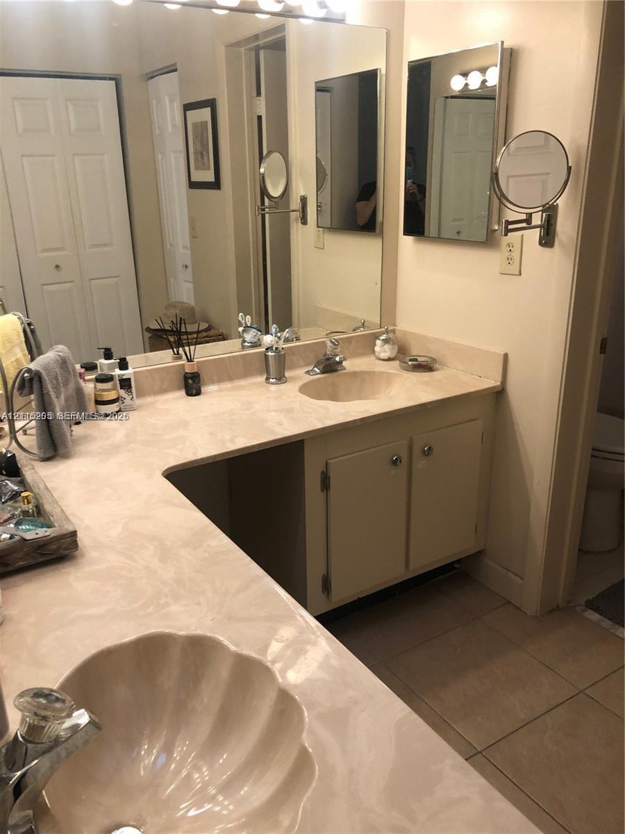Primary bathroom vanity with a continuous countertop, integrated dual sinks, solid-panel cabinetry, a full-width wall mirror.