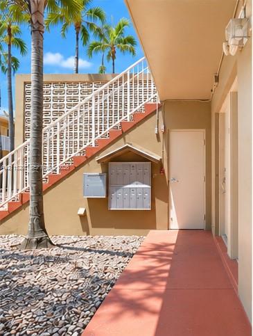 Exterior space featuring a concrete staircase with metal railings, decorative breeze block screening, built-in metal mailboxes, and paved ground cover