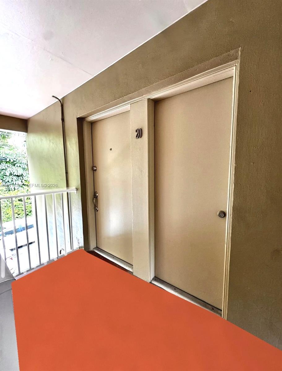 Exterior entry with painted stucco walls, dual access doors, and a metal safety railing Exterior entry with painted stucco walls, dual access doors, and a metal safety railing