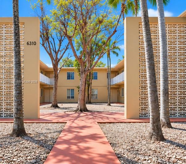 Mid-century exterior featuring decorative breeze block screening, a paved central courtyard walkway, and mature palms Mid-century exterior featuring decorative breeze block screening, a paved central courtyard walkway, and mature palms