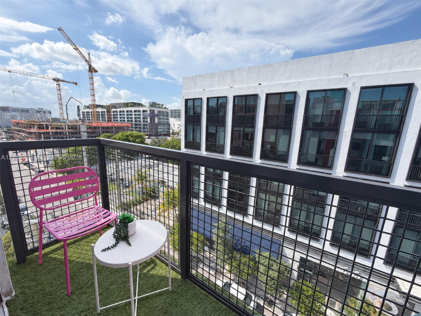 Private balcony featuring synthetic turf flooring and a black metal grid railing