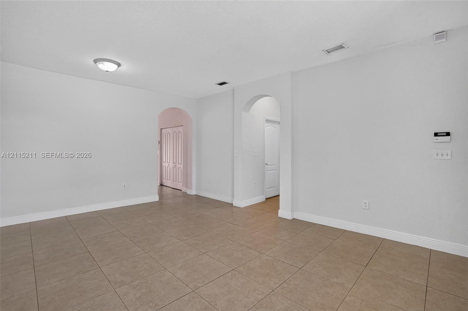 Open-concept interior featuring large-format neutral tile flooring and arched doorways