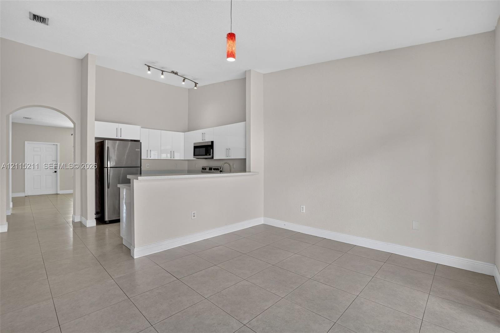 Kitchen featuring white flat-panel cabinetry, stainless steel appliances, a breakfast bar, and neutral floor tiling throughout