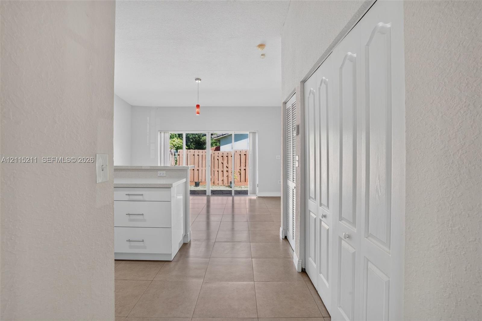 Ceramic tile flooring, white cabinetry with stone-finish countertops, and white paneled bifold closet doors