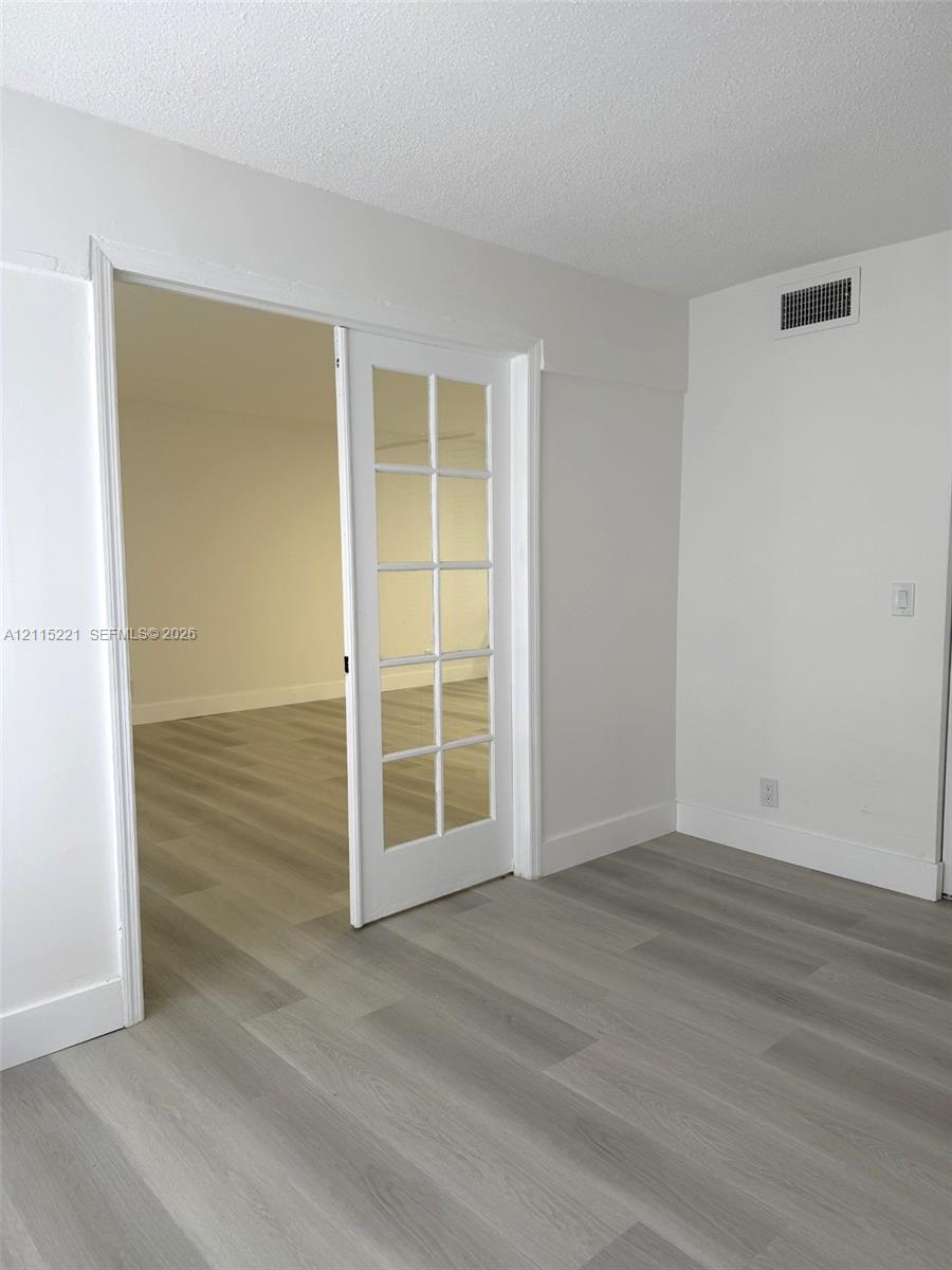 Interior space featuring white-painted walls, wood-finish flooring, and a glass-paned French door